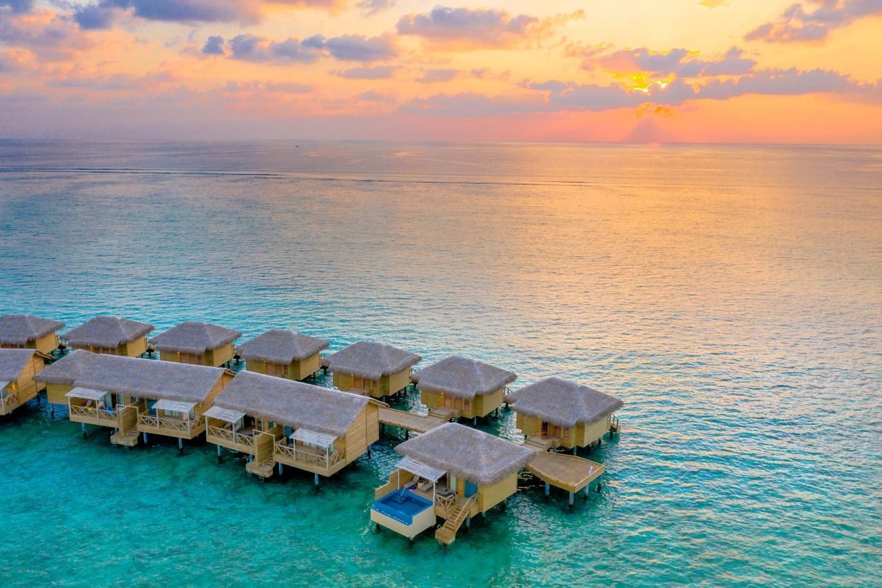 Aerial view of Maldives overwater villas at sunset